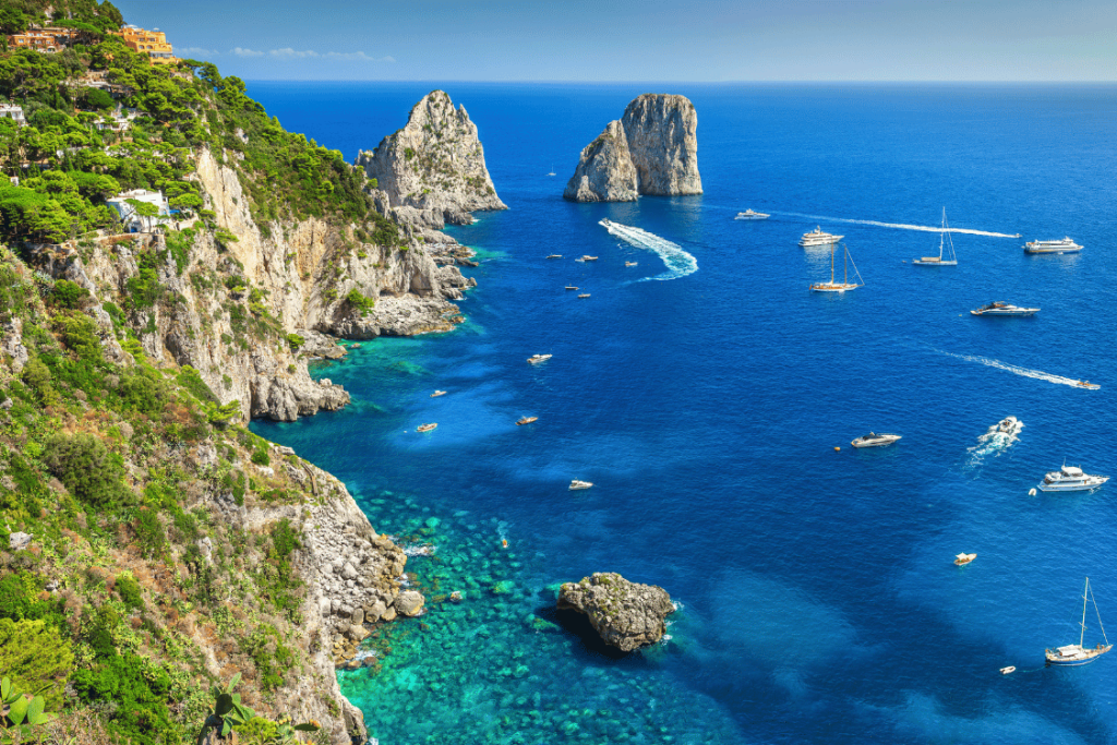 Vista panoramica della costa e dei Faraglioni di Capri in Costiera Amalfitana, con barche ancorate in rada
