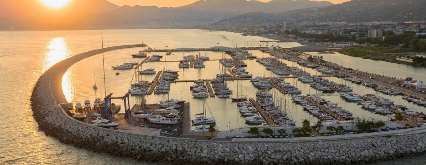 Vista aerea del Marina d'Arechi di Salerno al tramonto con barche ormeggiate in porto.